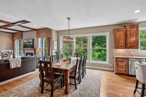 The dining room and adjacent living room are filled with natural light from tall windows that frame the space beautifully.