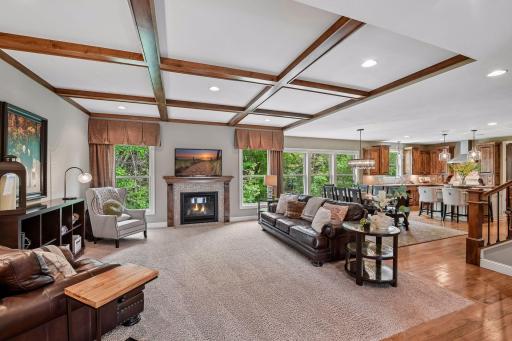 This wide view of the main level living spaces showcases the full coffered ceiling detail in the living room, accented by recessed lighting
