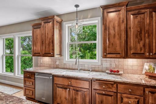 A bright kitchen sink area with a window, tile backsplash, and under-cabinet lighting that provides excellent workspace illumination