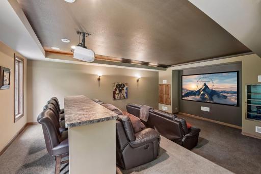 The theatre room features a 8.5'x5' screen, a tray ceiling w/ crown molding detail, wall sconces and a 9' bar seating.