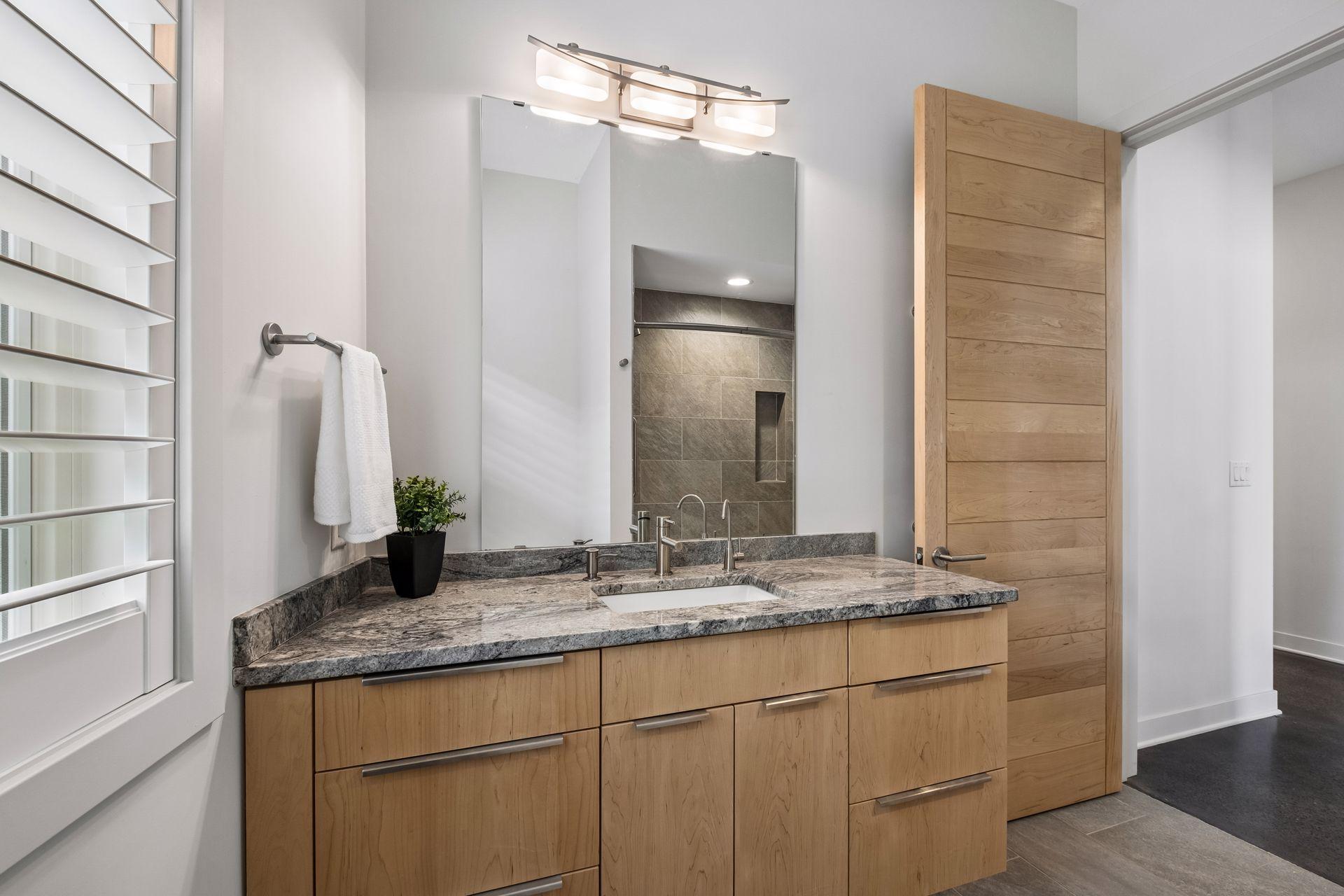 Beautiful lower-level full bath with heated tile flooring, granite custom vanity, tile surround shower w/cast-iron tub. Don't forget the plantation wood shutters throughout. Such a nice touch.