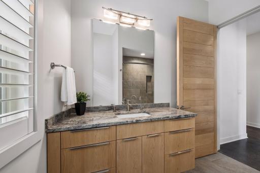 Beautiful lower-level full bath with heated tile flooring, granite custom vanity, tile surround shower w/cast-iron tub. Don't forget the plantation wood shutters throughout. Such a nice touch.