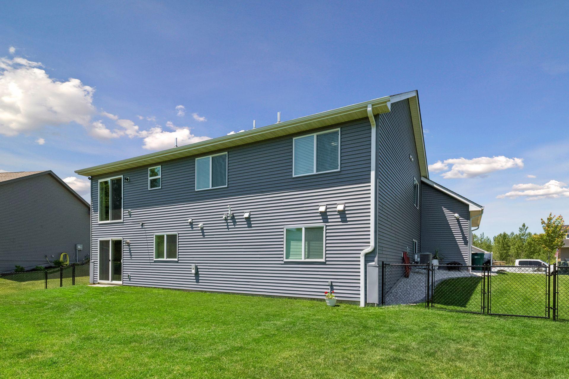Back of home showing fence, new gutters and nice flat backyard.