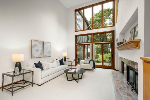 Expansive windows above drawing in natural light and framing the wooded setting and immaculate gardens and landscaped grounds.