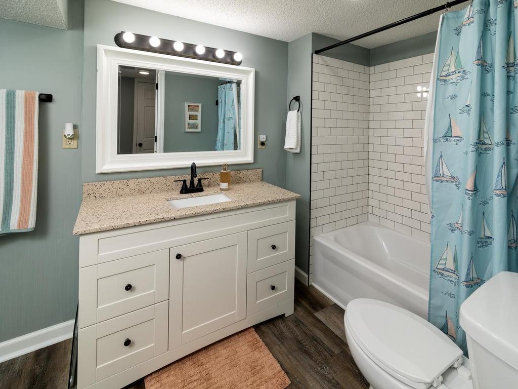 Lower-level full bath with subway-tiled tub surround & updated vanity lighting