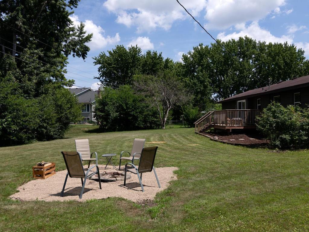 Back of the home with deck, mature shrubs & perennial beds