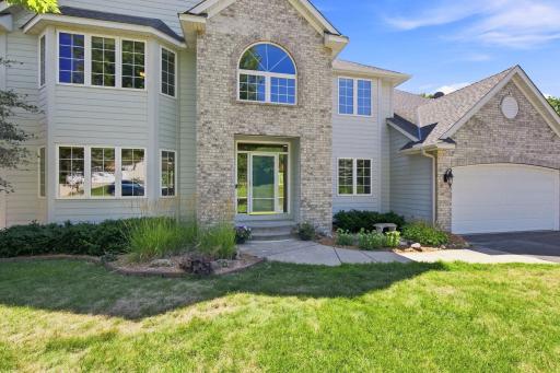 Grand front entrance welcomes guests with soaring architecture, oversized arched window, professional landscaping, and a covered entryway. An inviting first impression that reflects the quality found throughout this luxury Lakeville home.