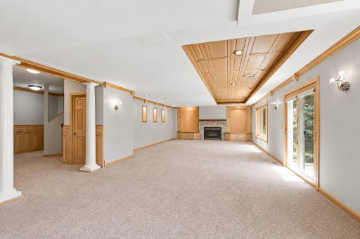 Walkout family room with fireplace, custom built-ins, and wooded backyard views.