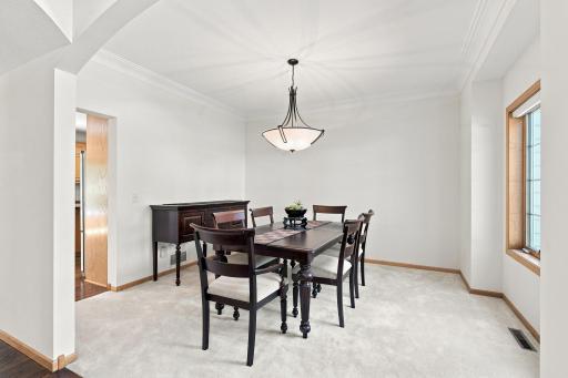 Formal dining room offers an elegant space for entertaining with large windows, crown molding, and easy access to the kitchen.