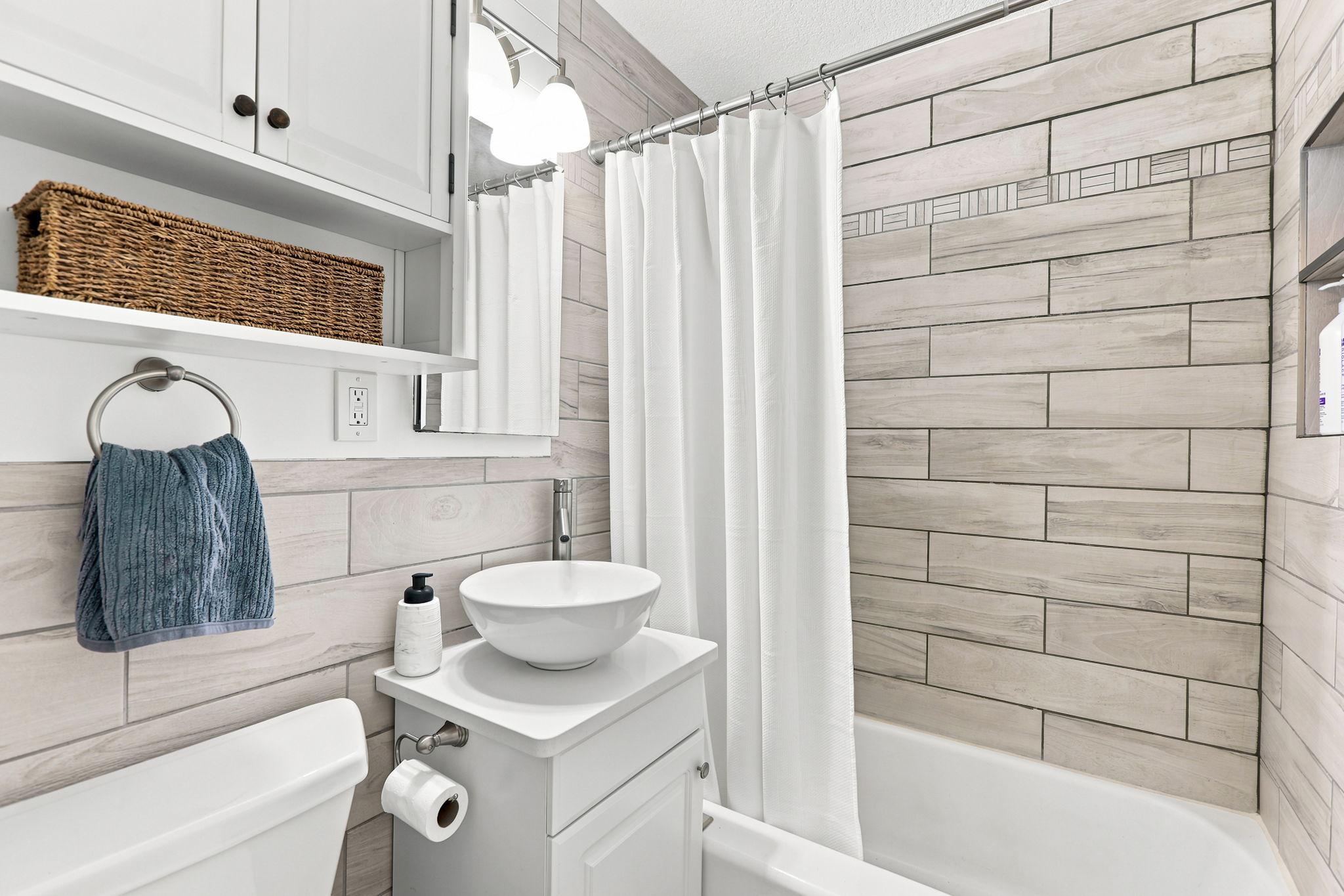 Updated main level full bath complete with tile, updated vanity and modern lighting!