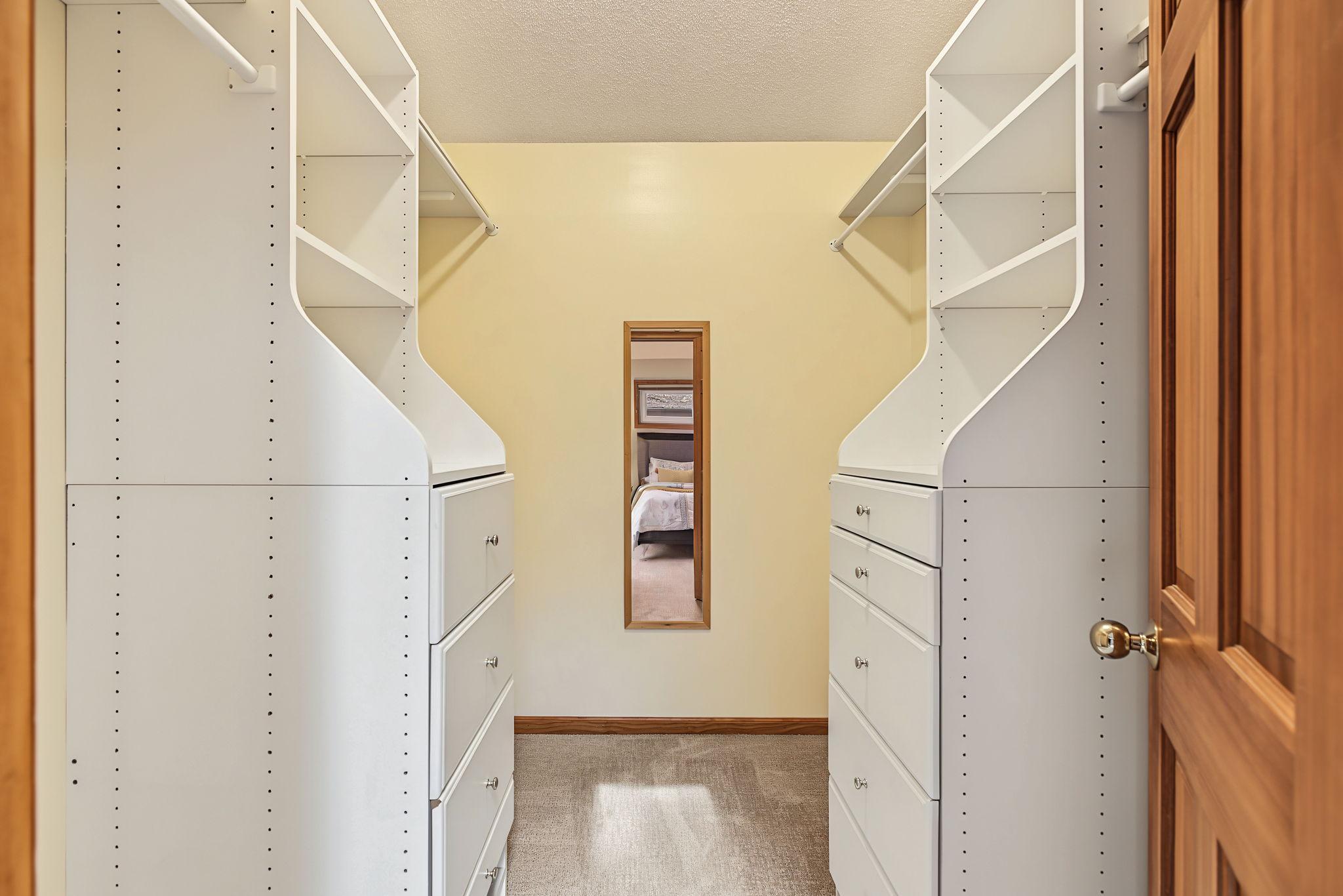 Walk in closet features custom storage solutions.
