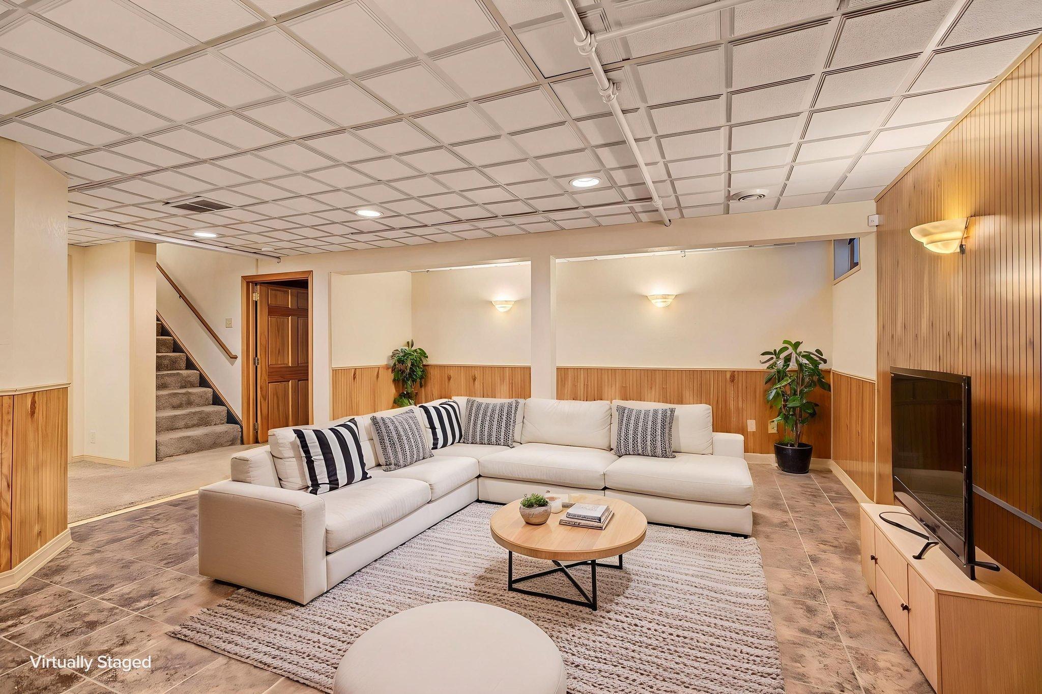 The lower level offers even more space for folks to spread out! This room has been digitally staged and the wall color was digitally altered to help a potential buyer envision how a little paint could completely transform this space!