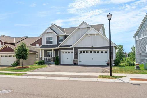 Wide street-level shot highlighting the home's impressive exterior, clean sidewalk framing, and charming street light.