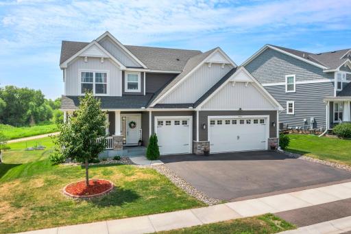 Welcoming entrance featuring a cozy front porch, decorative stone pillars, and manicured mulched garden bed.