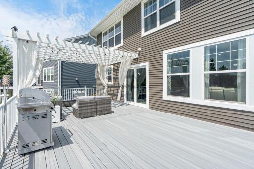 Spacious elevated deck off the main living level featuring modern low-maintenance composite decking, sliding glass door access, and a custom pergola structure.