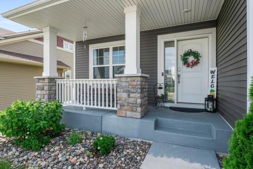 Up-close perspective of the front porch, highlighting the detailed stone columns, front porch seating space, and bright entryway door.