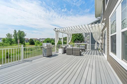 Expansive low-maintenance composite deck featuring a custom pergola, outdoor dining/lounge area, and open views.