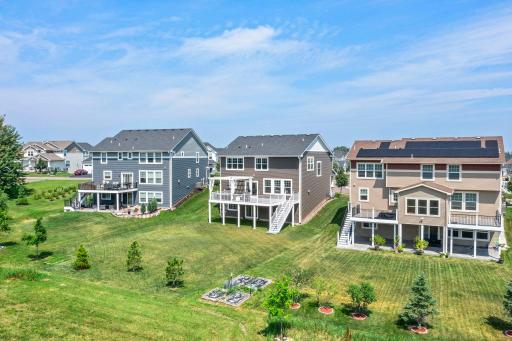 Aerial perspective showcasing the home alongside neighboring properties, backed by open green lawn areas and garden beds.