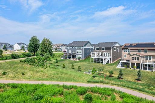High-angle view showing the home's proximity to the community paved walking trail and surrounding natural greenbelt.