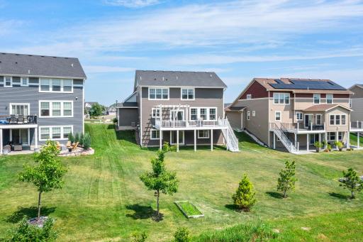 Elevated ground-level view framing the expansive backyard, garden plots, and clean exterior architecture.