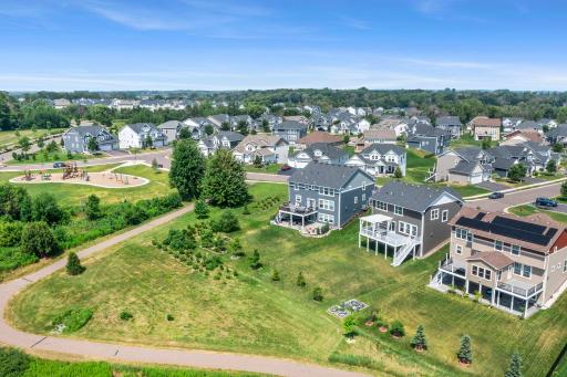 Wide aerial perspective highlighting the surrounding neighborhood, nearby park/playground, and connected walking paths