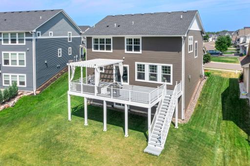 Close elevated perspective of the spacious composite deck, white railings, overhead pergola, and lower walkout patio access.