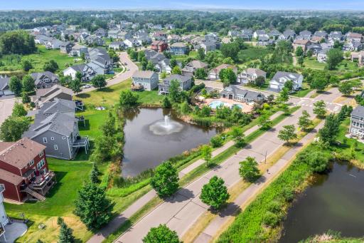 Aerial view capturing the community fountain pond, paved trail system, outdoor pool area, and surrounding homes.
