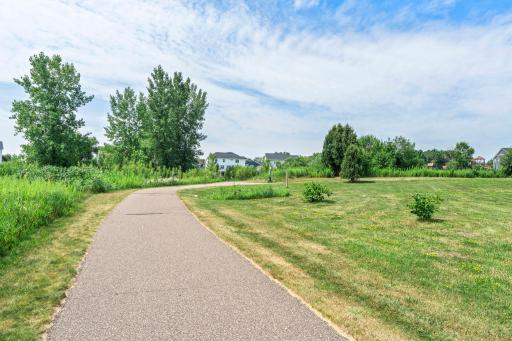 View of the paved neighborhood walking path running directly adjacent to the surrounding green space.