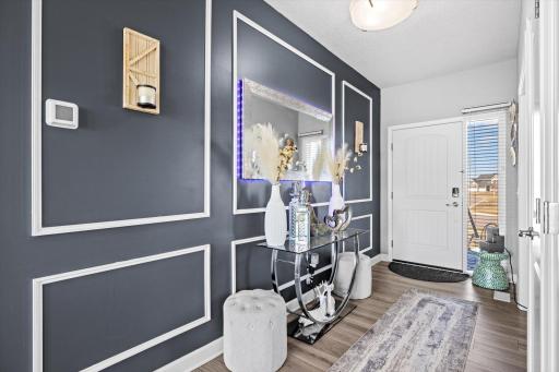 Bright front entryway featuring custom wall molding, luxury vinyl flooring, and direct access to the main living areas.
