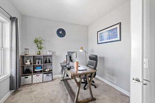 Dedicated main-floor office space complete with cozy carpeting, generous natural light, and quiet privacy.