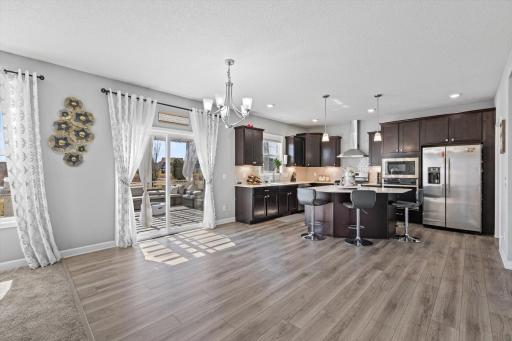 Open-concept dining space with luxury vinyl plank flooring and sliding glass door access to the rear outdoor deck.