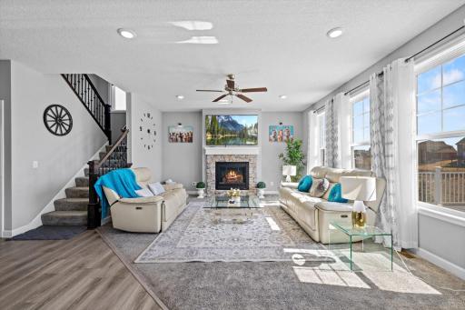 Cozy living room centered around a stone-surround gas fireplace, surrounded by large windows that flood the room with natural light.