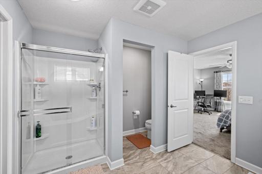 Includes a separate walk-in glass shower, private water closet, and easy access back to the primary bedroom suite.