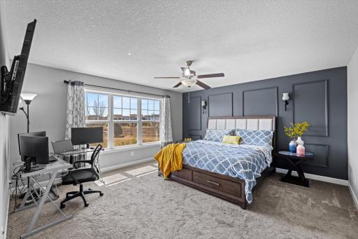 Expansive primary bedroom featuring a dark accent wall with custom accent trim, plush carpeting, and space for a sitting area or desk.