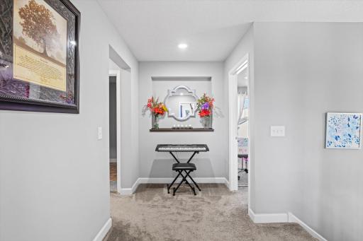 Character-rich hallway foyer with plush carpeting, built-in recessed display niche, and functional layout connecting upper-level rooms.