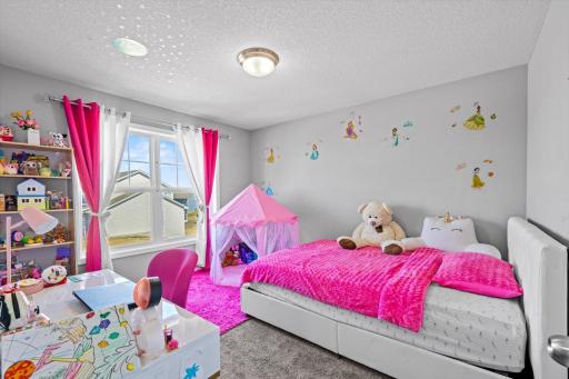 Charming additional bedroom featuring plush carpeting, generous natural light from large windows, and ample space for bedroom furniture or play areas.