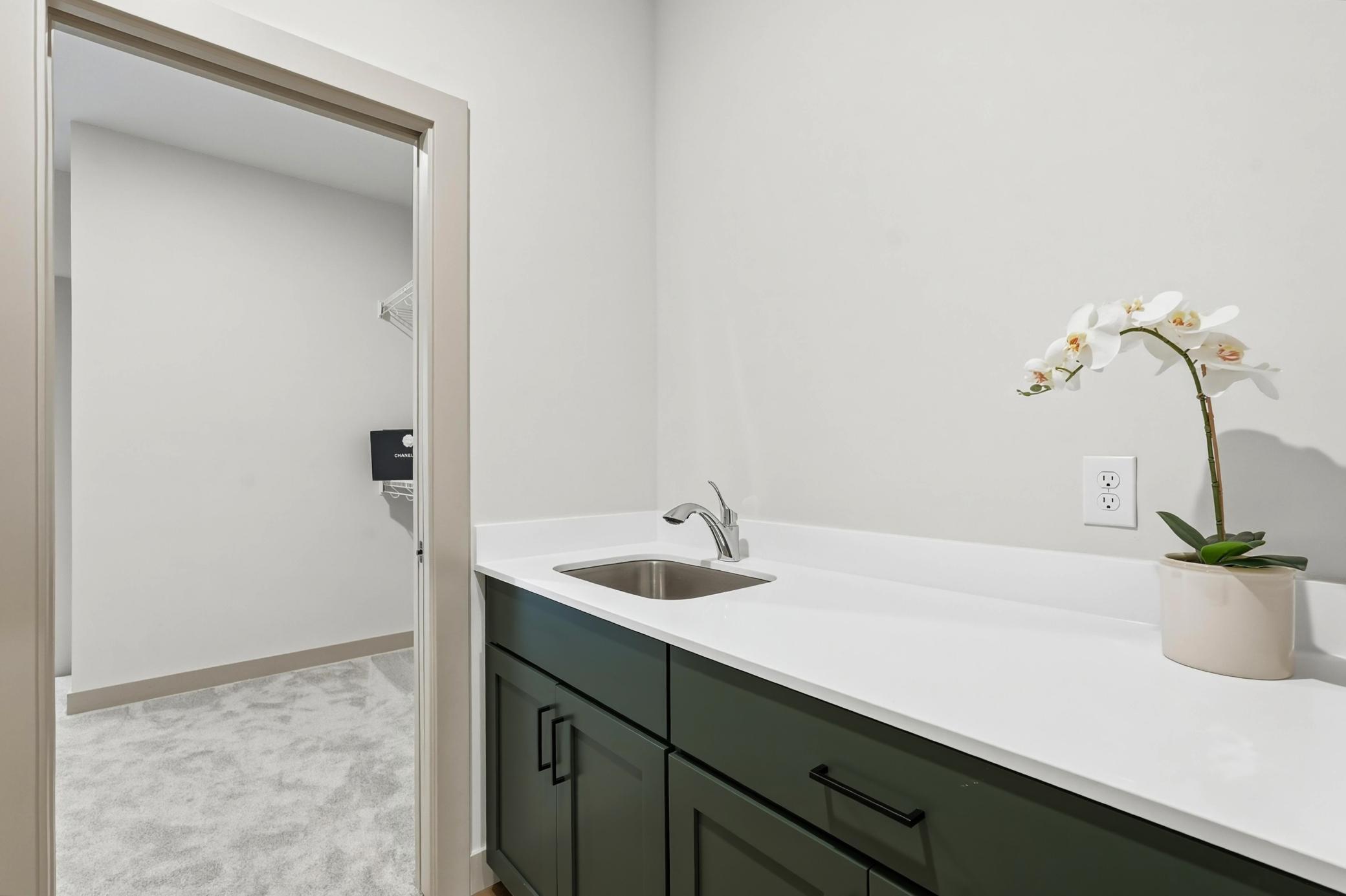 Laundry Room & Utility Station
Highly functional laundry room boasting custom deep-green cabinetry, generous quartz folding countertops, a stainless steel utility sink, and direct access to an adjacent walk-in closet.