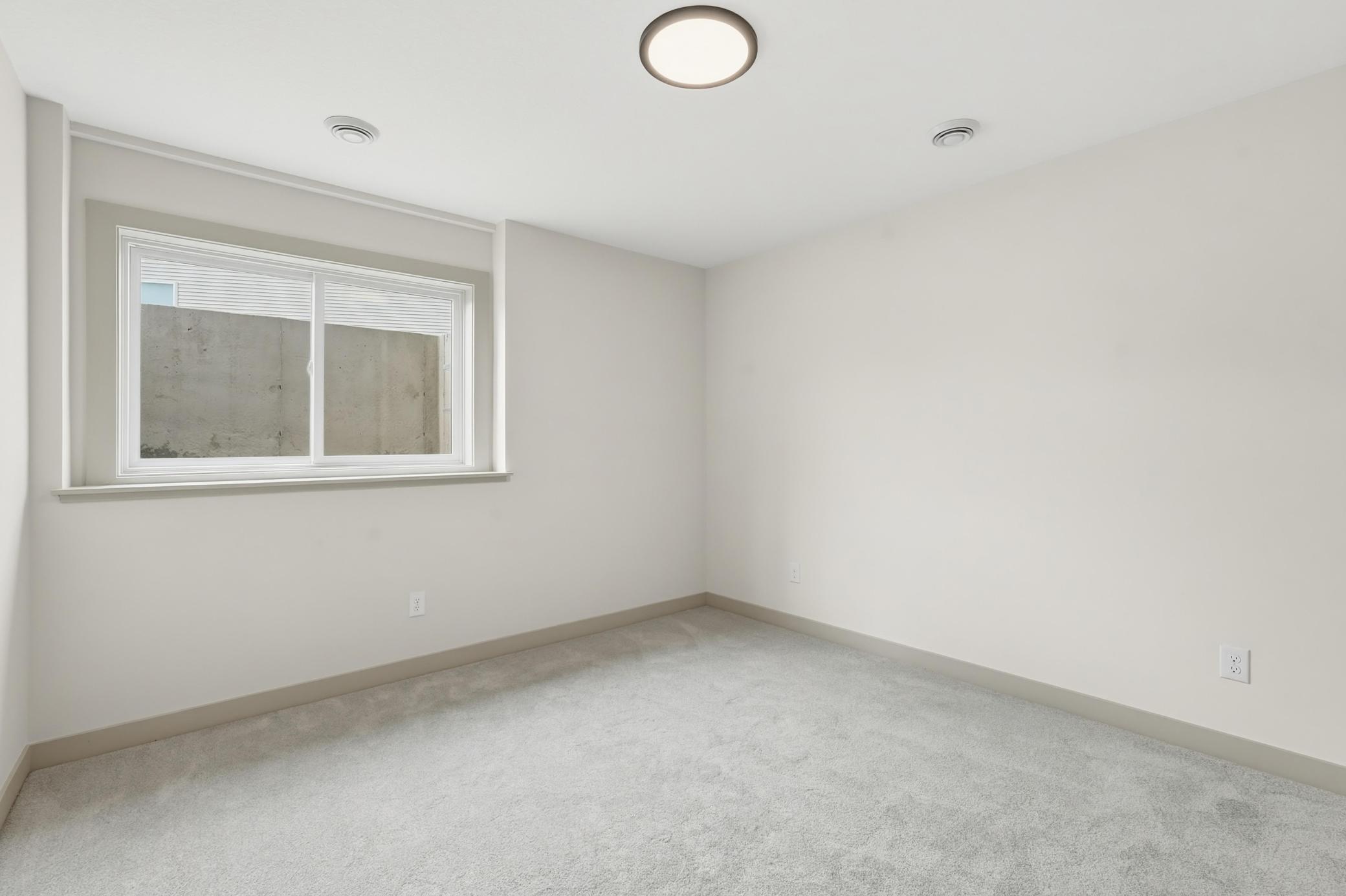 Lower-Level Guest Bedroom Cozy lower-level bedroom offering plush carpet, neutral finishes, and an egress window providing natural light for guests or a home office.