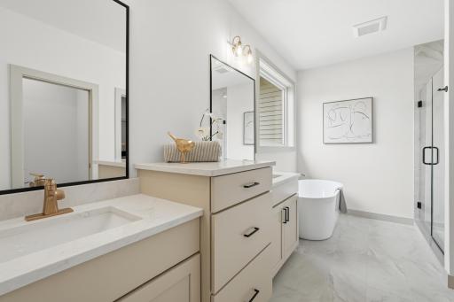 Primary En-Suite Spa Bath
Luxurious spa-inspired primary bathroom featuring staggered dual vanities, luxury champagne-bronze and black fixtures, a freestanding soaking tub under a sunlit window, and a custom glass-enclosed tiled shower.
