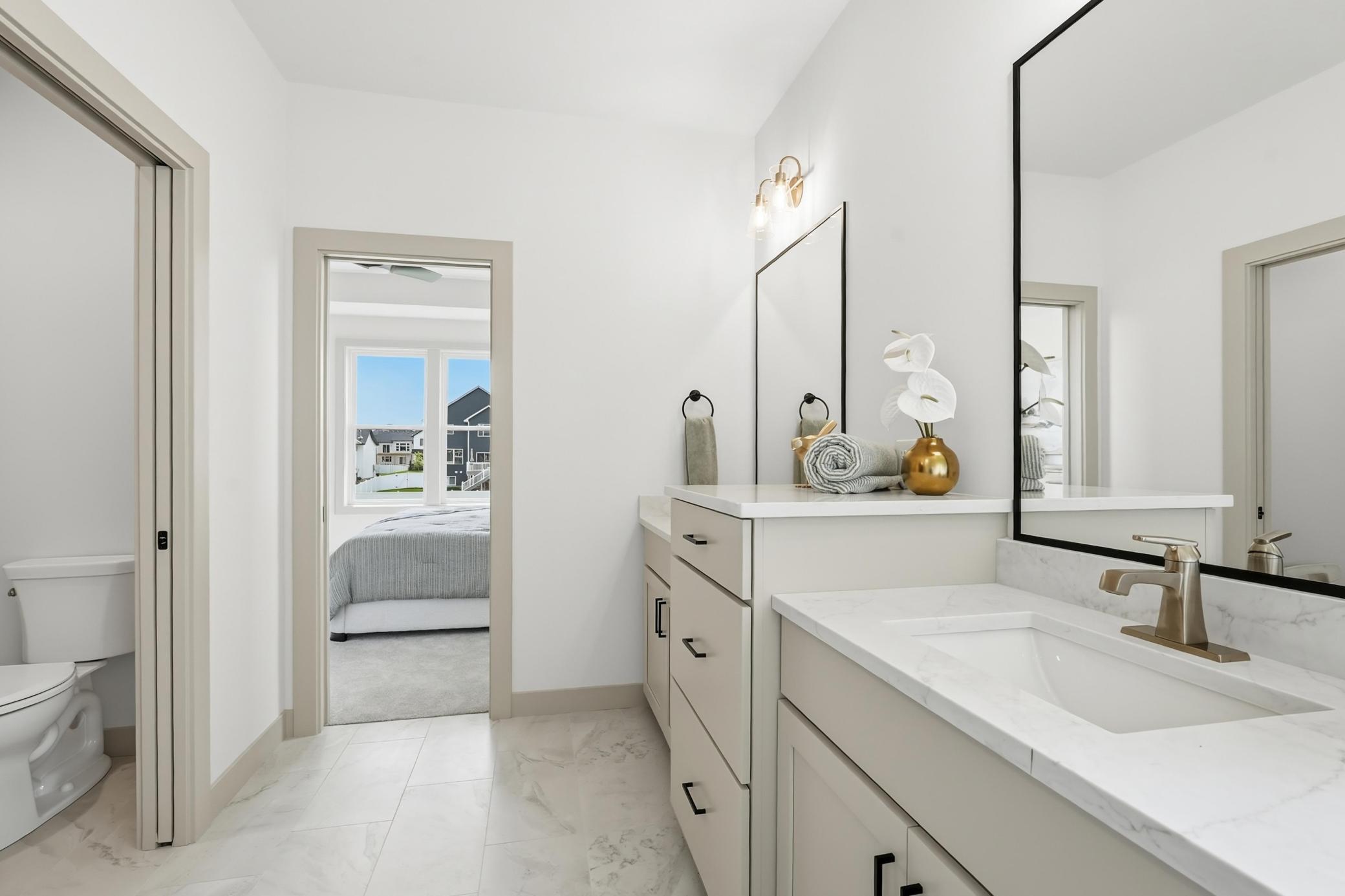 Primary En-Suite Layout
Functional primary bathroom layout showcasing the double vanity design, marble-look tiled flooring, private water closet room, and direct, convenient access into the primary bedroom suite.