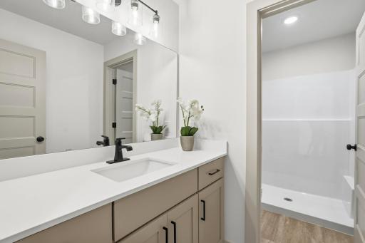 Well-appointed bathroom featuring a single-sink vanity with white quartz counters, matte black hardware, updated vanity lighting, and a separate walk-in shower room.
