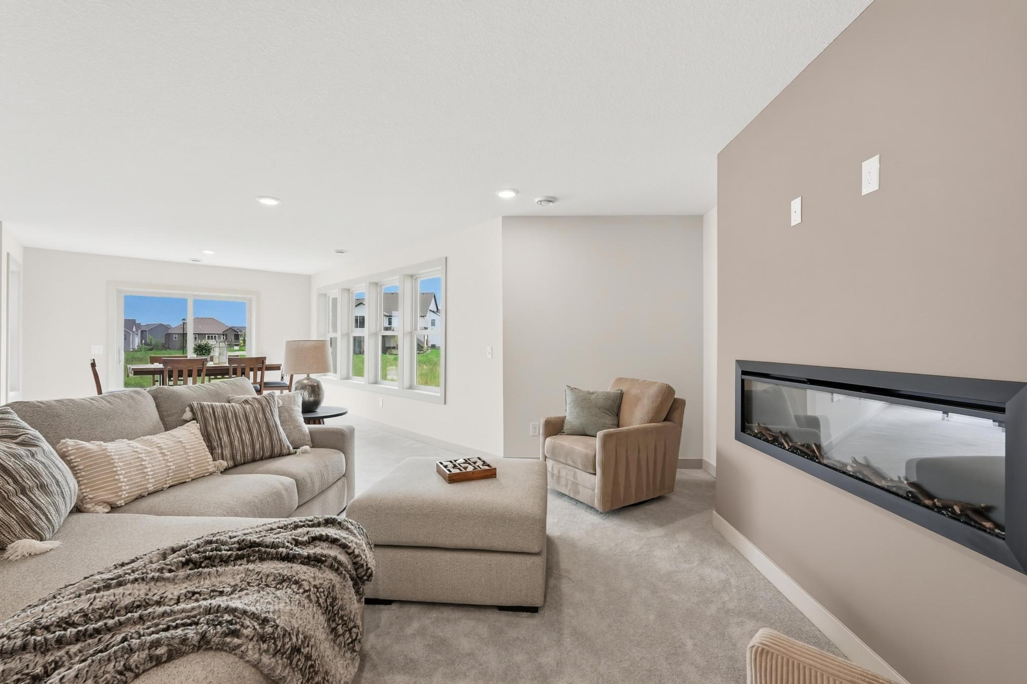 Lower-Level Rec Space & Walkout
Bright, flexible basement living area offering ample space for media and gaming setups, framed by a wall of windows and sliding door walkout access to the yard.