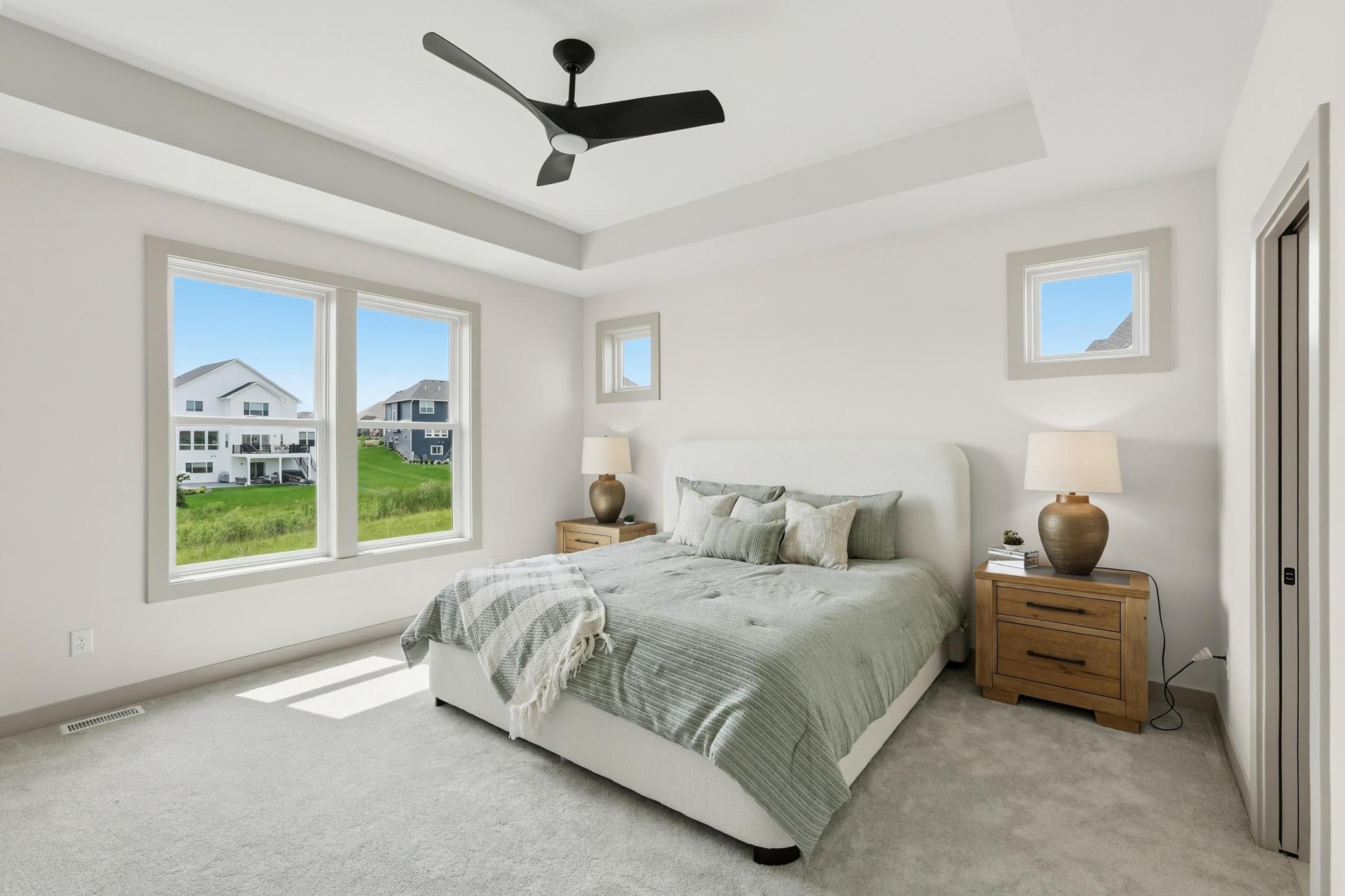 Primary Suite
Tranquil primary bedroom featuring an architectural tray ceiling with a modern ceiling fan, high accent windows for privacy, and wide picture windows bringing in scenic outdoor views.