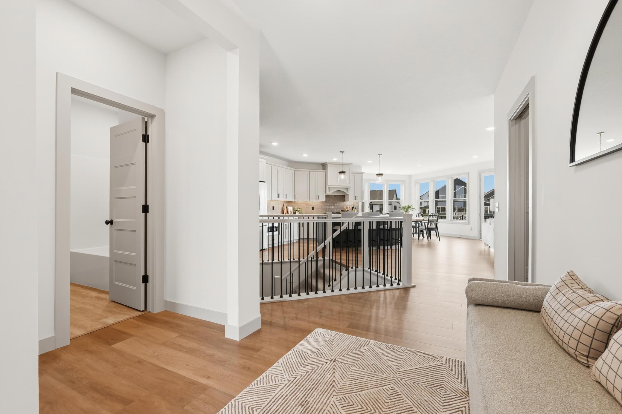 Welcoming main entryway featuring warm plank flooring, sleek modern spindle railings, and an open-concept flow that leads seamlessly into the heart of the home while offering sightlines to the lower level.