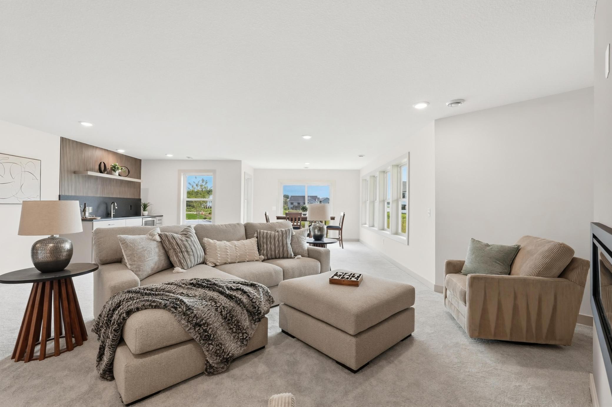 Lower-Level Family Room
Expansive lower-level entertaining space bathed in natural light from full-sized windows, featuring soft plush carpet, a cozy seating layout, and effortless flow to the wet bar.