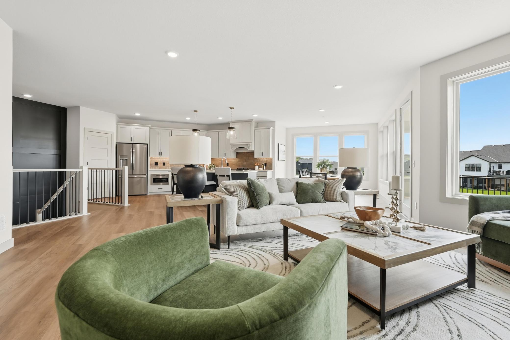 Expansive open-plan living room highlighting the effortless flow between the main seating area, kitchen, and dining room, surrounded by wall-to-wall windows and rich natural light.
