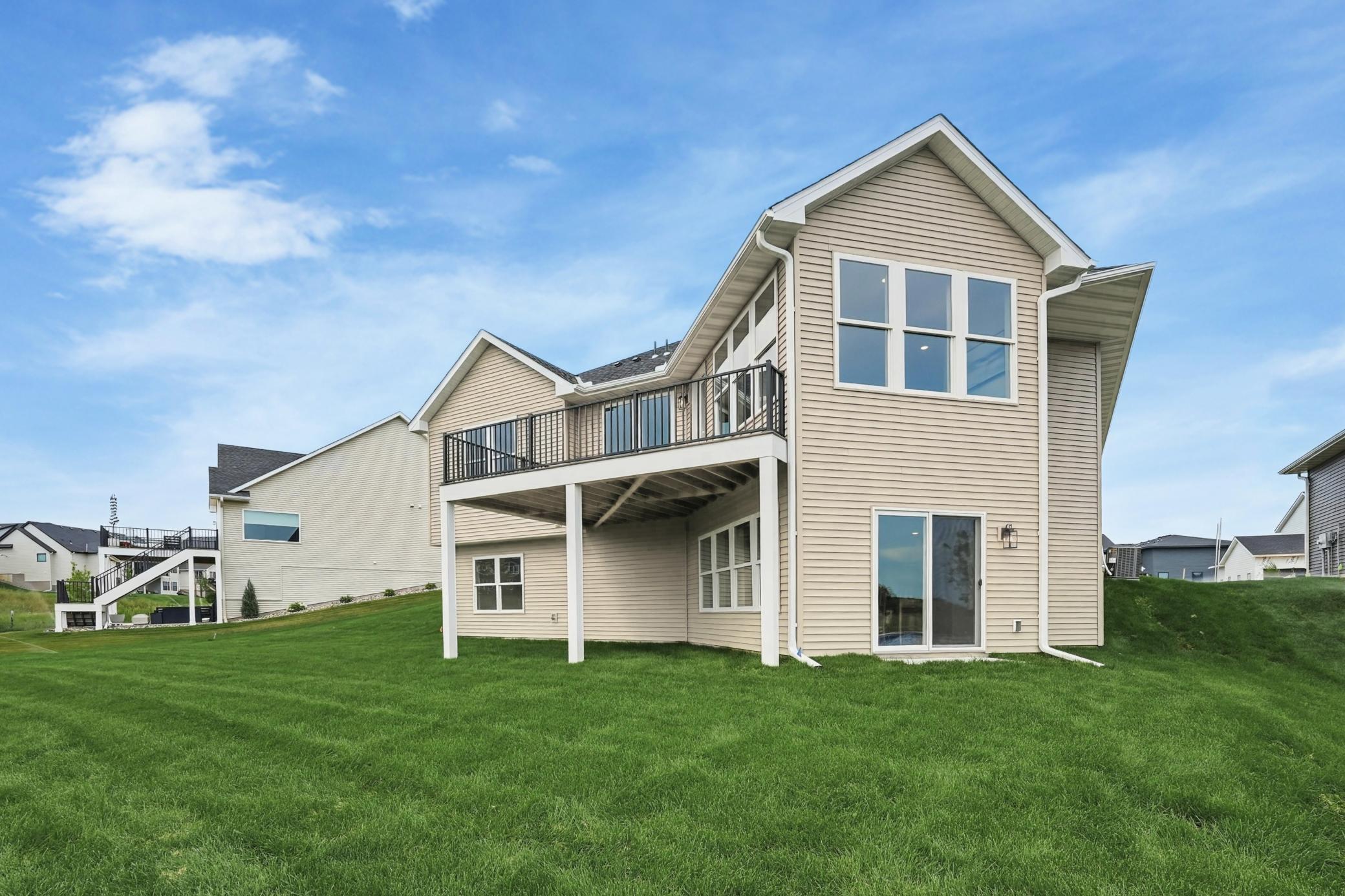 Rear Elevation & Sprawling Yard
Impressionable rear view showcasing the walkout lower level, elevated deck, clean architectural lines, and expansive manicured green lawn.