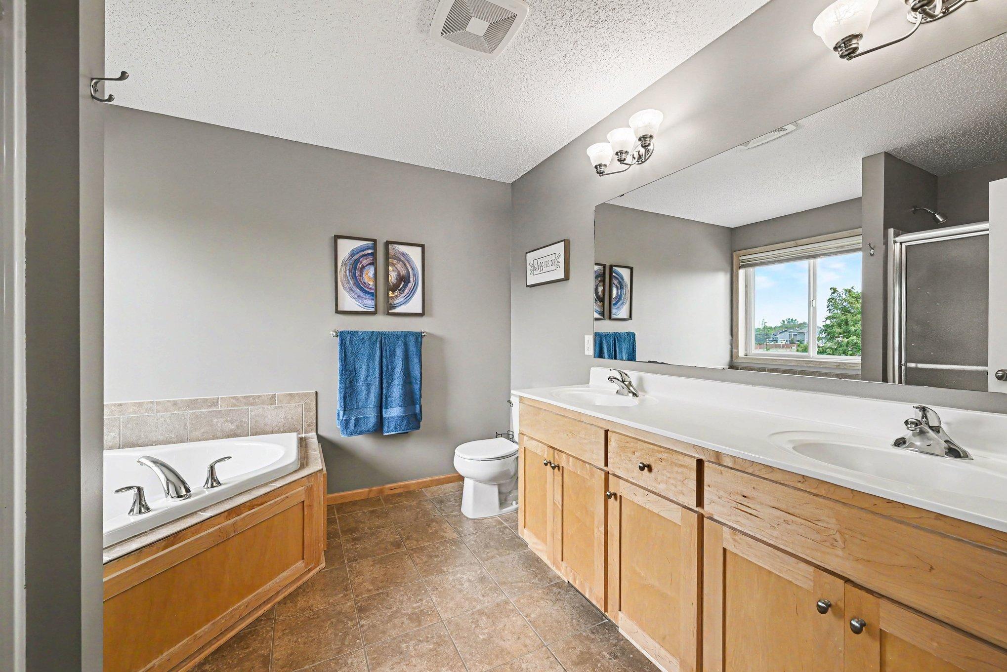 Primary bath with dual sinks, separate shower, and jetted tub