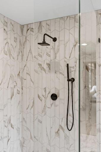 New primary shower with black plumbing fixtures and frameless glass.