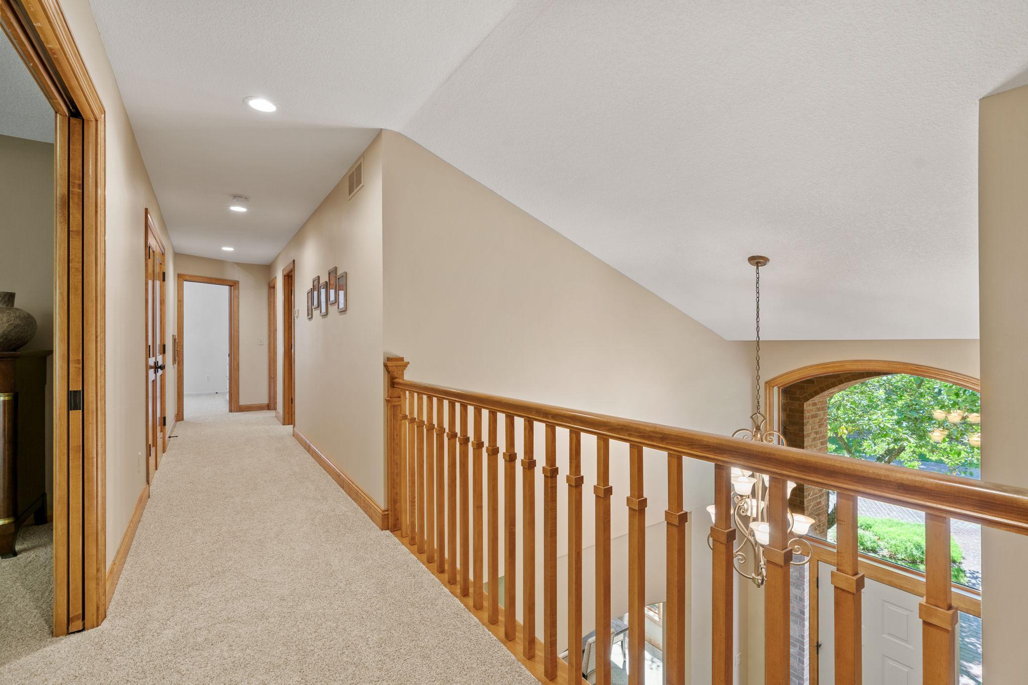 Upper level hall overlooks vaulted foyer.